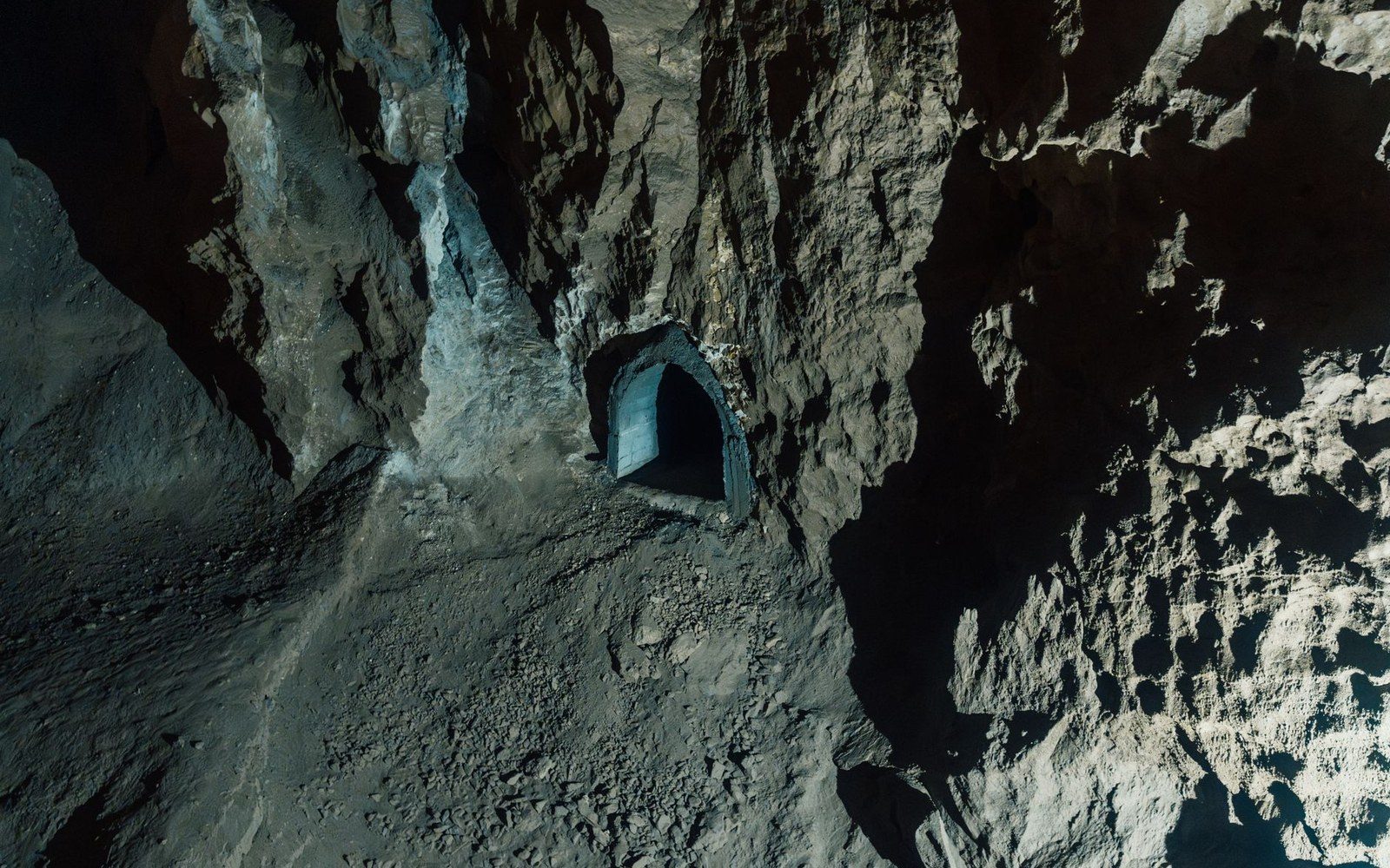 Arched tunnel entrance carved into a steep, rocky mountainside